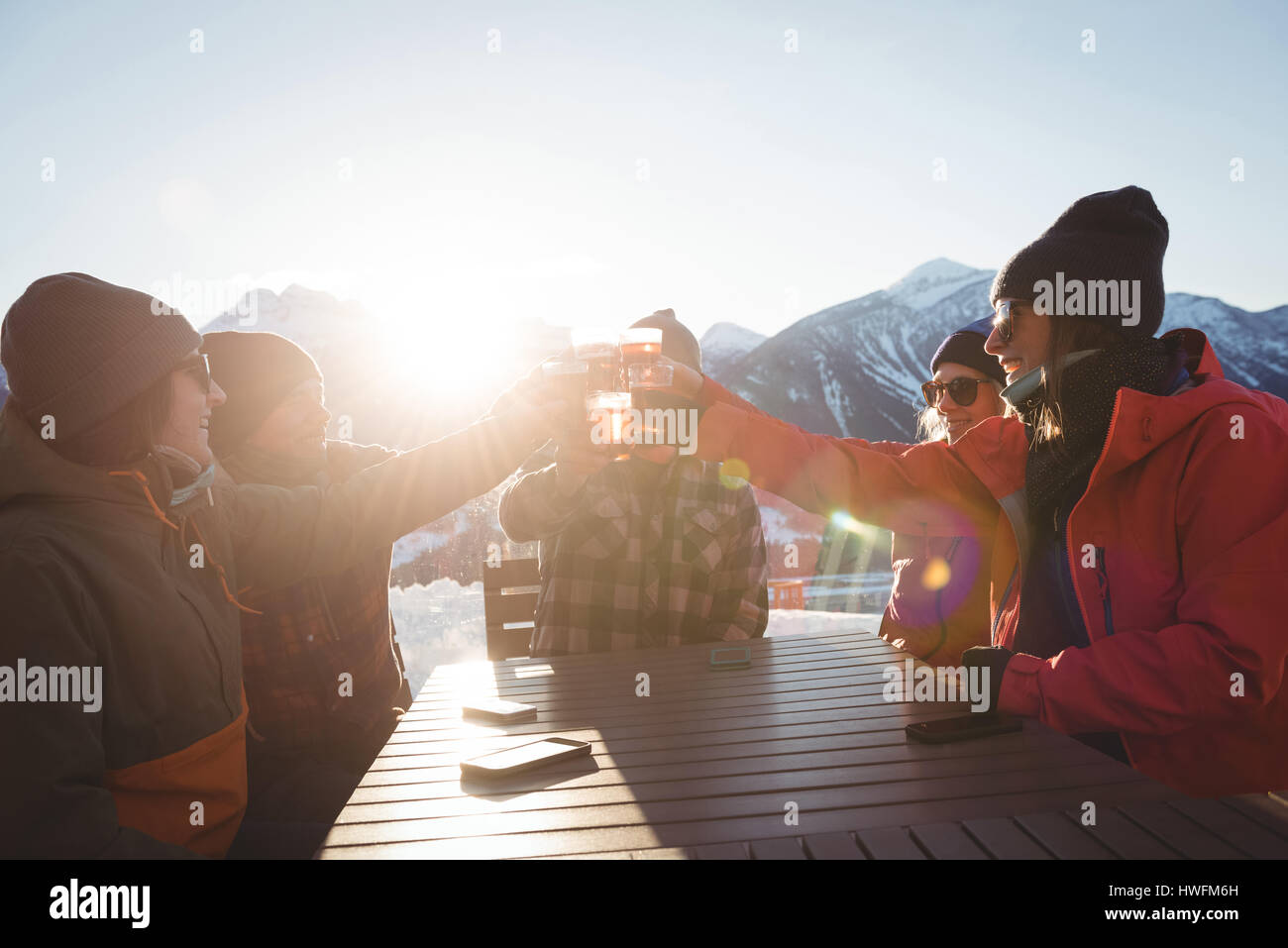 Gli sciatori amici tostatura di bicchieri di birra in ski resort su una brillante luce solare Foto Stock