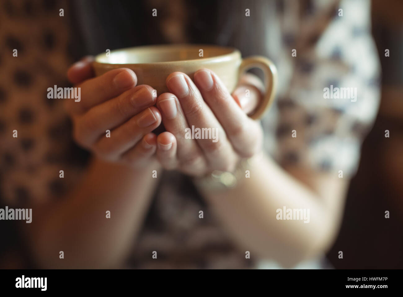 La sezione centrale della donna che mantiene una tazza di caffè in cafÃƒÂ© Foto Stock