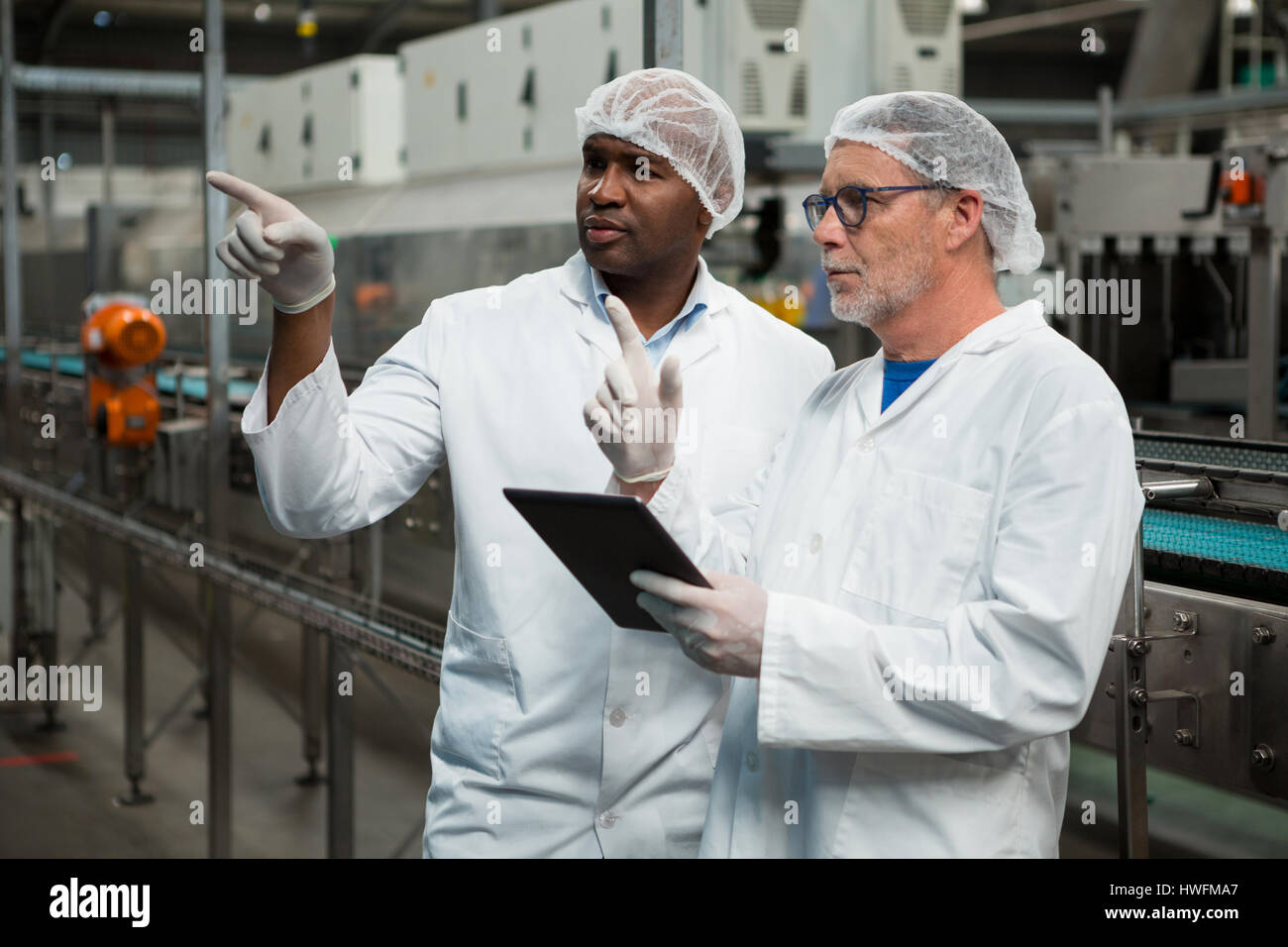 I lavoratori di sesso maschile di ispezionare i prodotti nella bevanda fredda factory Foto Stock