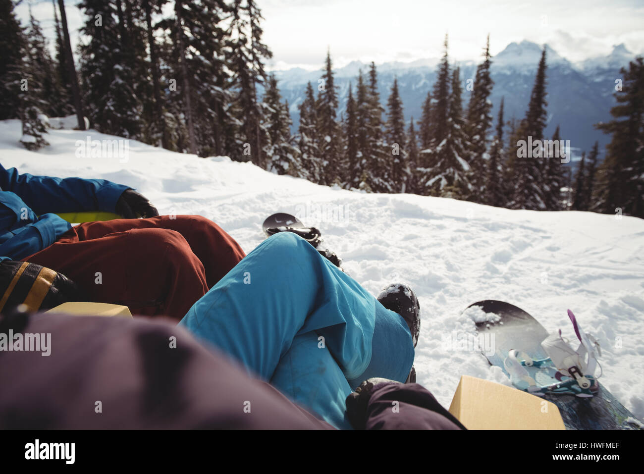Sezione bassa del giovane seduto alla coperta di neve montagna Foto Stock