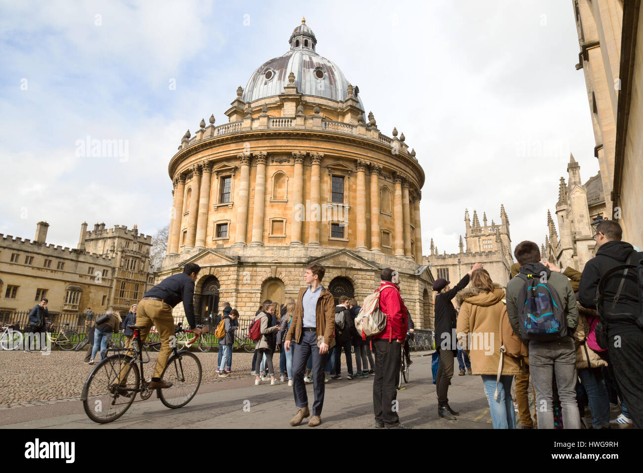 Oxford Inghilterra centro città, persone pedalando attraverso la Radcliffe Camera, Oxford Regno Unito Foto Stock