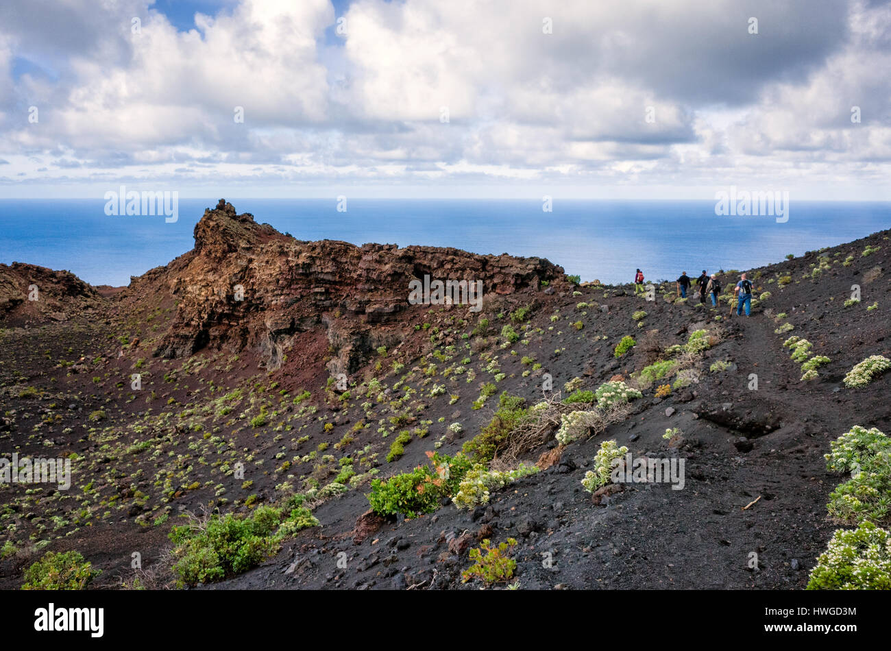 Cumbre Vieja, Fuencaliente. La Palma. Una vista lungo il vulcano della cresta di avvolgimento e geologico formazione di terra. Molto poca vegetazione ad eccezione di Echium Brevirame crescente nella roccia lavica di Cumbre Vieja regione. La giornata è luminosa con il veloce movimento di nuvole. Gli escursionisti a piedi lungo il crinale sulle tracce di sentiero. Foto Stock