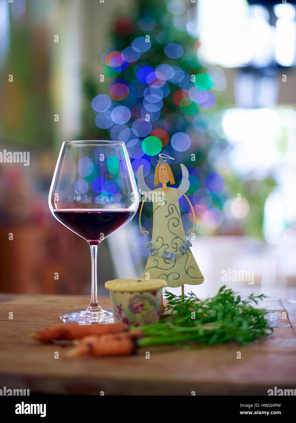 Vino rosso di vetro nella parte anteriore degli alberi di Natale con luci di decorazione trattare per Santa Foto Stock