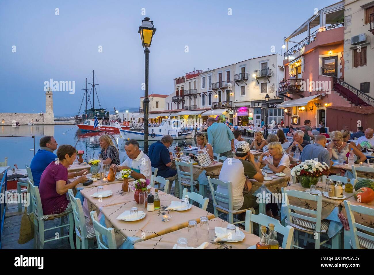 La Grecia, Creta, Rethymnon, città vecchia, terrazza di ristoranti nel vecchio porto veneziano del XV secolo veneziano del faro in background Foto Stock