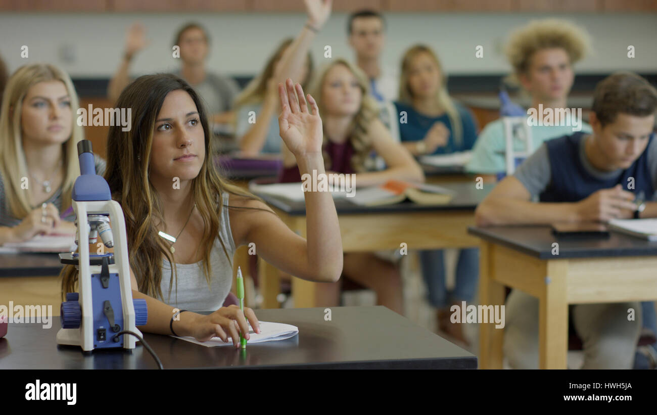 Studente curioso alzando la mano per rispondere alla domanda nel laboratorio di scienze aula Foto Stock