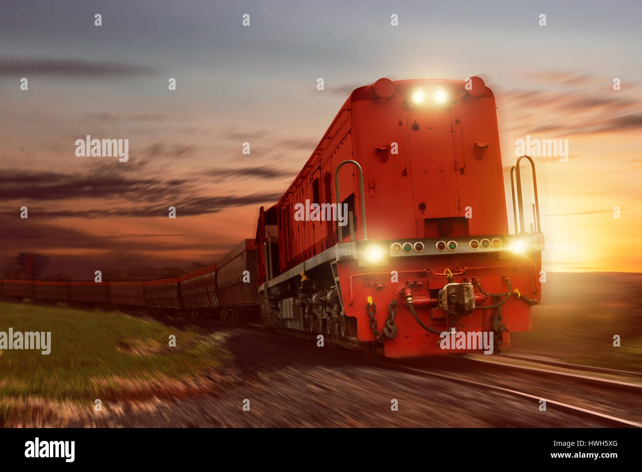 Treno merci con carico vetture che trasportano carbone al tramonto Foto Stock