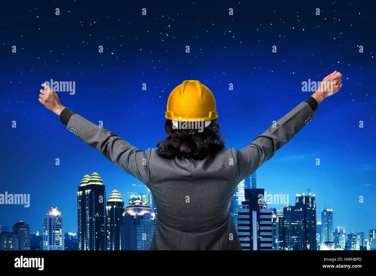 Vista posteriore architetto di alzare la mano guardando la città Foto Stock