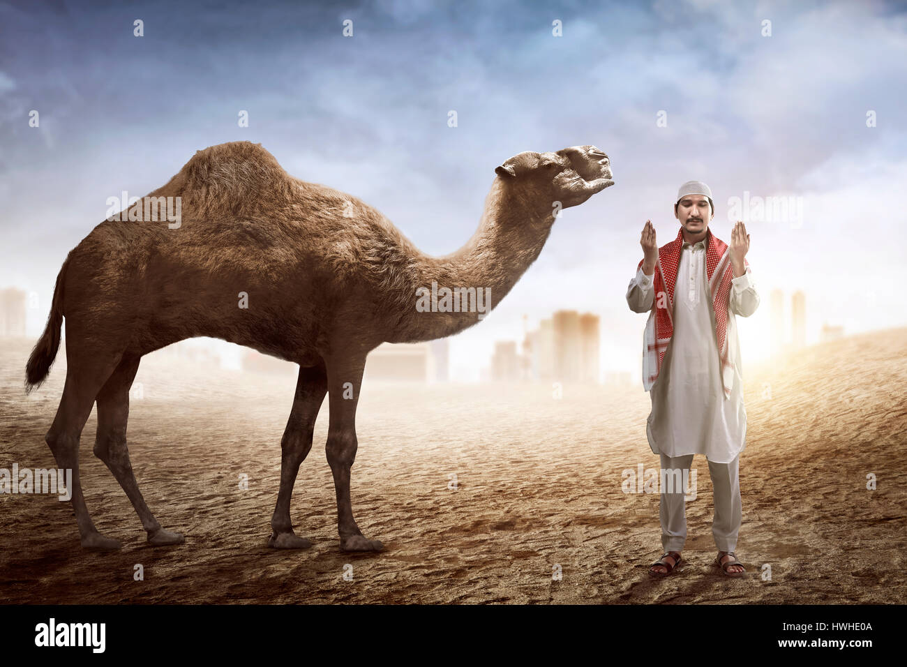 Immagine dell uomo che prega e cammello con lo sfondo del deserto Foto Stock