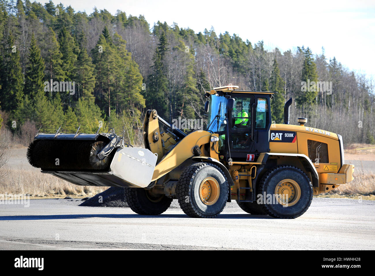 PAIMIO, Finlandia - 18 Marzo 2017: CAT 938 K ruota il caricatore e la benna spazzatrice al lavoro per pulire un asfalto cortile a molla. Foto Stock
