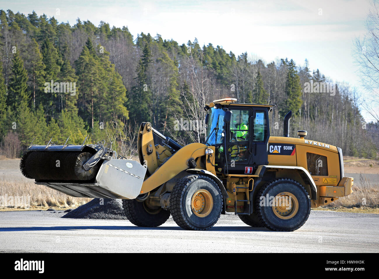 PAIMIO, Finlandia - 18 Marzo 2017: CAT 938 K ruota il caricatore e la benna spazzatrice al lavoro per pulire un asfalto cortile a molla. Foto Stock