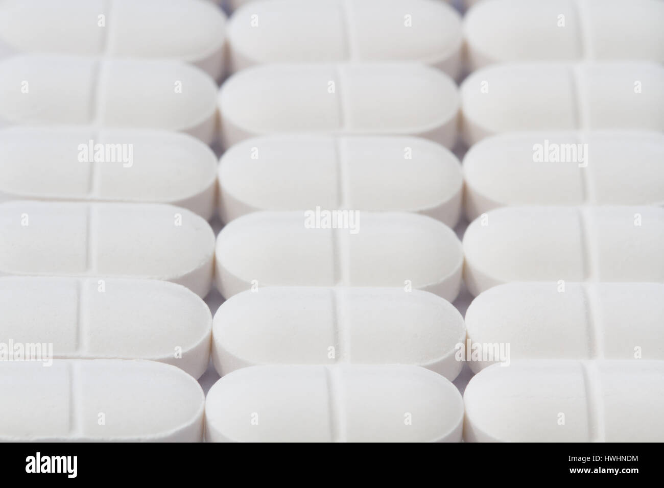 Righe bianche di sollievo dal dolore compresse, pillole, farmaci e la medicina in un medico di immagine di sfondo che rappresentano il settore della produzione di farmaci. Foto Stock