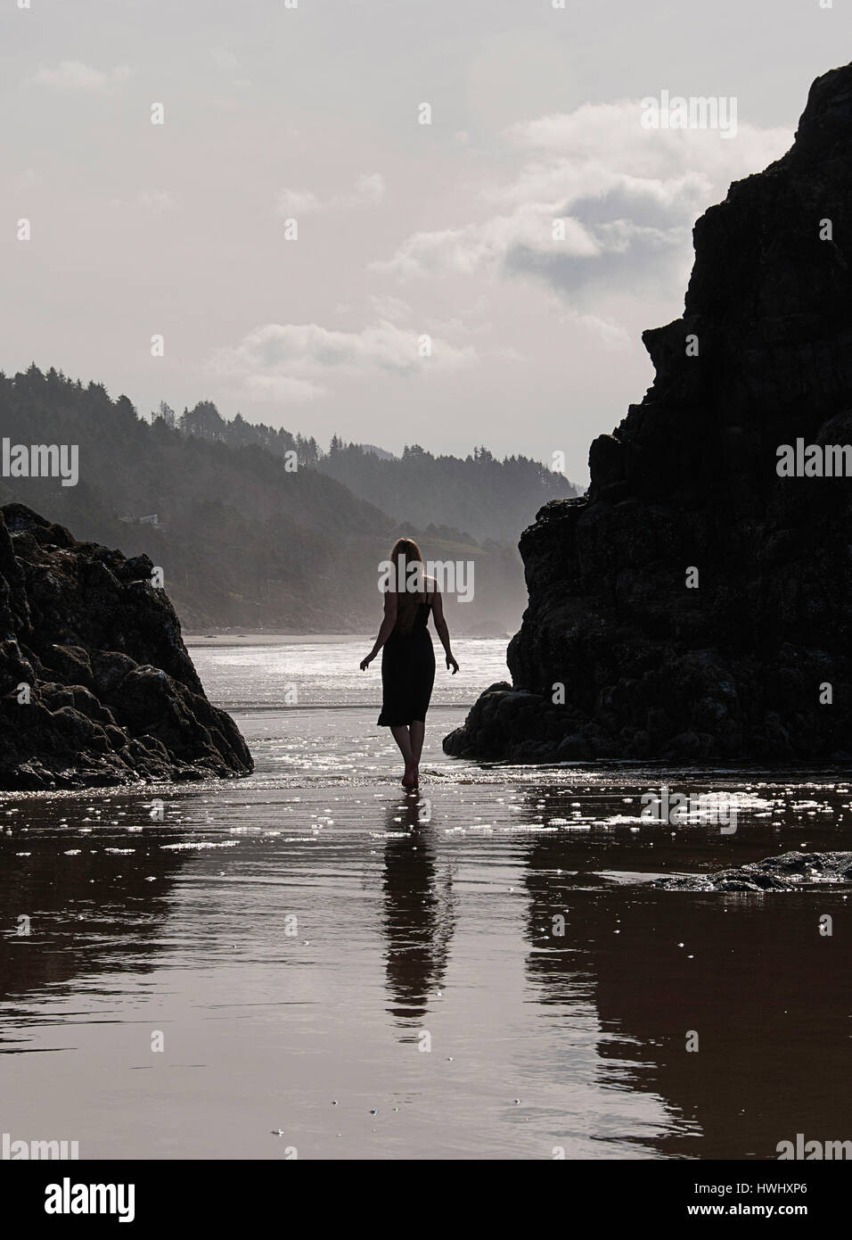 Una donna in piedi in acqua sulla costa dell'Oregon. Foto Stock