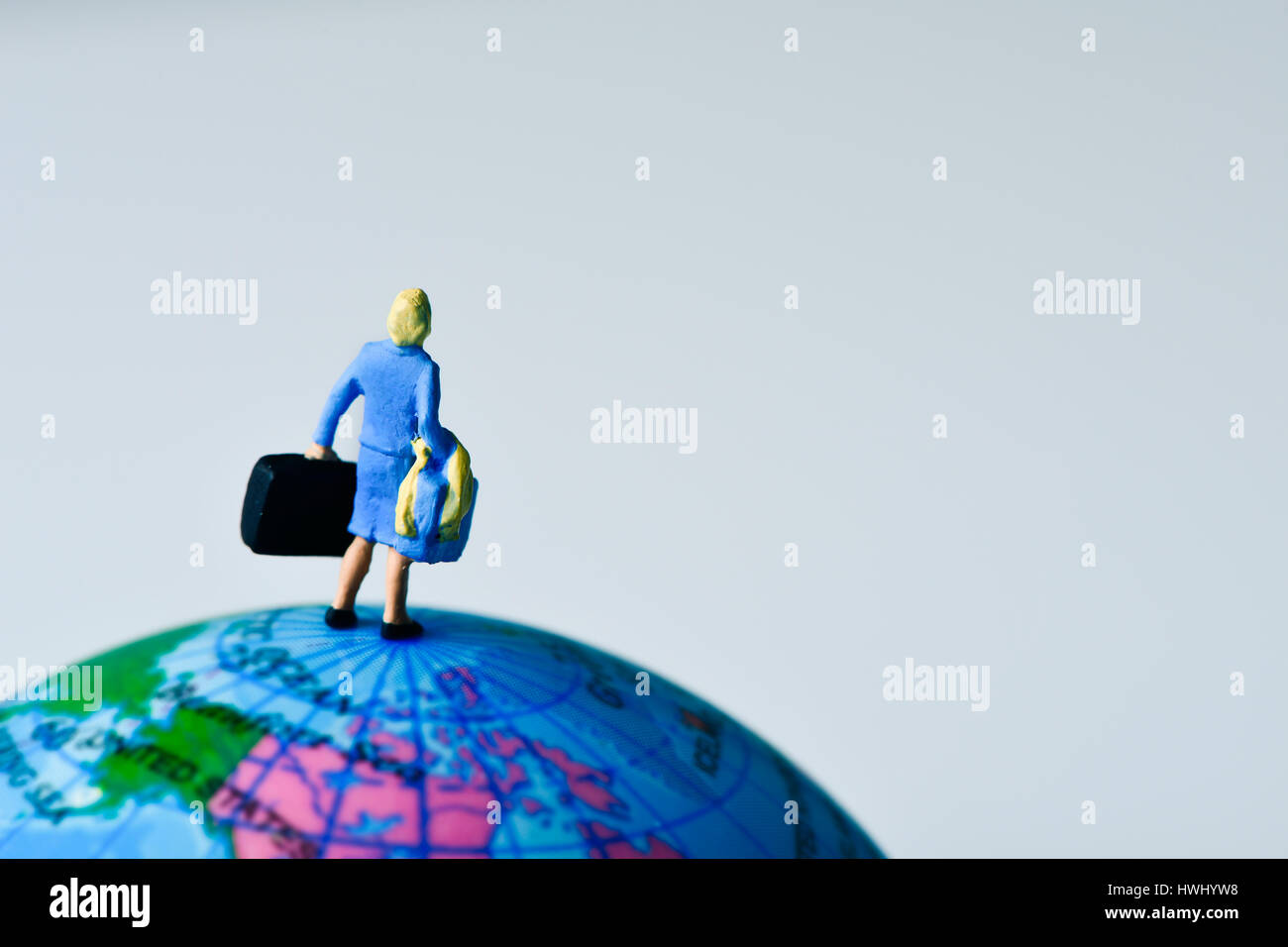 Viaggiatore in miniatura donna visto da dietro portando alcune valigie, sulla parte superiore del globo terrestre Foto Stock
