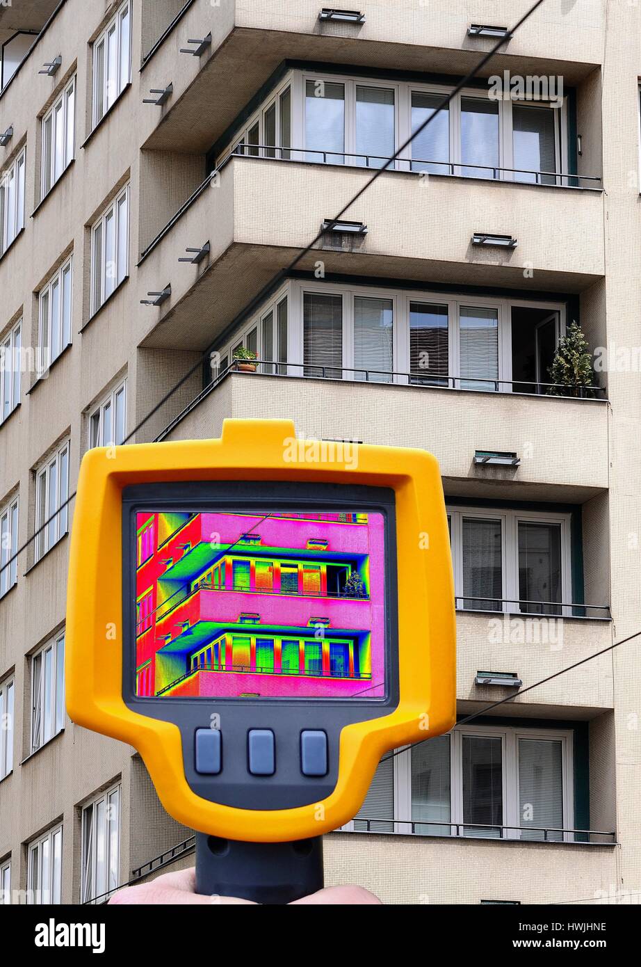 Registrare la perdita di calore del blocco di appartamenti con termocamera infrarossa in mano. Foto Stock