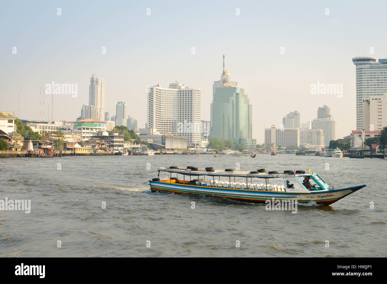 Bangkok, Tailandia - 18 Febbraio 2017: Colorful barca si avvicina al molo mentre alcuni di Bangkok skyline è visto sullo sfondo. Foto Stock