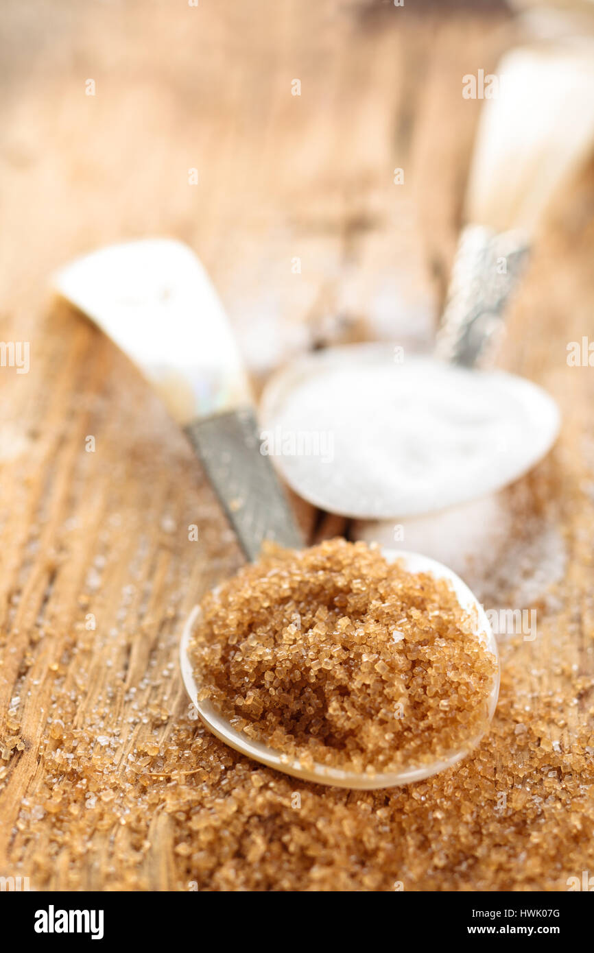 Lo zucchero di canna nel cucchiaio su tavola in legno rustico. Foto Stock