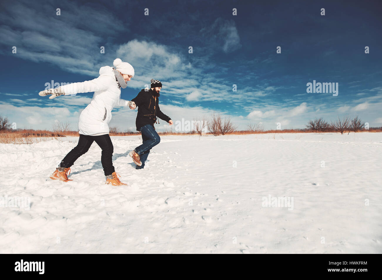 Concetto di famiglia felice vita, vacanze invernali, escursione. ragazza ragazzo ANS che eseguono sul campo nevoso oltre il bel cielo azzurro sfondo Foto Stock