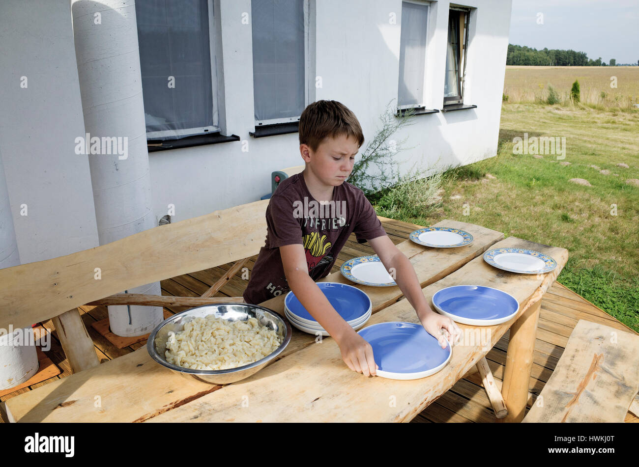 Ragazzo le piastre di impostazione per la cena sul tavolo da picnic sul ponte 10 anni d'età. Zawady Polonia centrale Europa Foto Stock