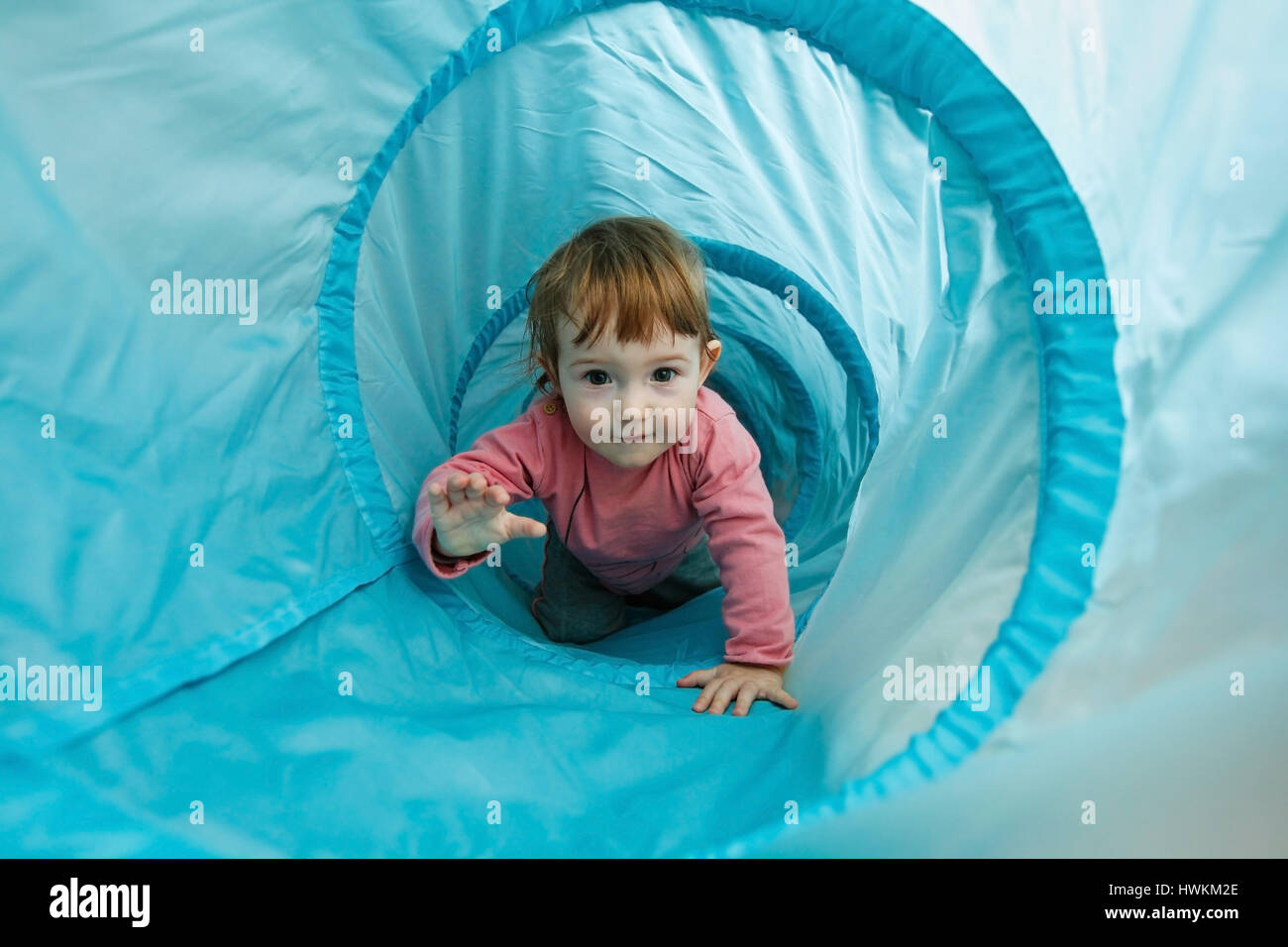 Piccolo bimbo giocando in un tunnel tubo, strisciando attraverso di esso e divertirsi. E per il divertimento di tutta la famiglia, inizio l educazione e l apprendimento attraverso l esperienza del concetto. Foto Stock