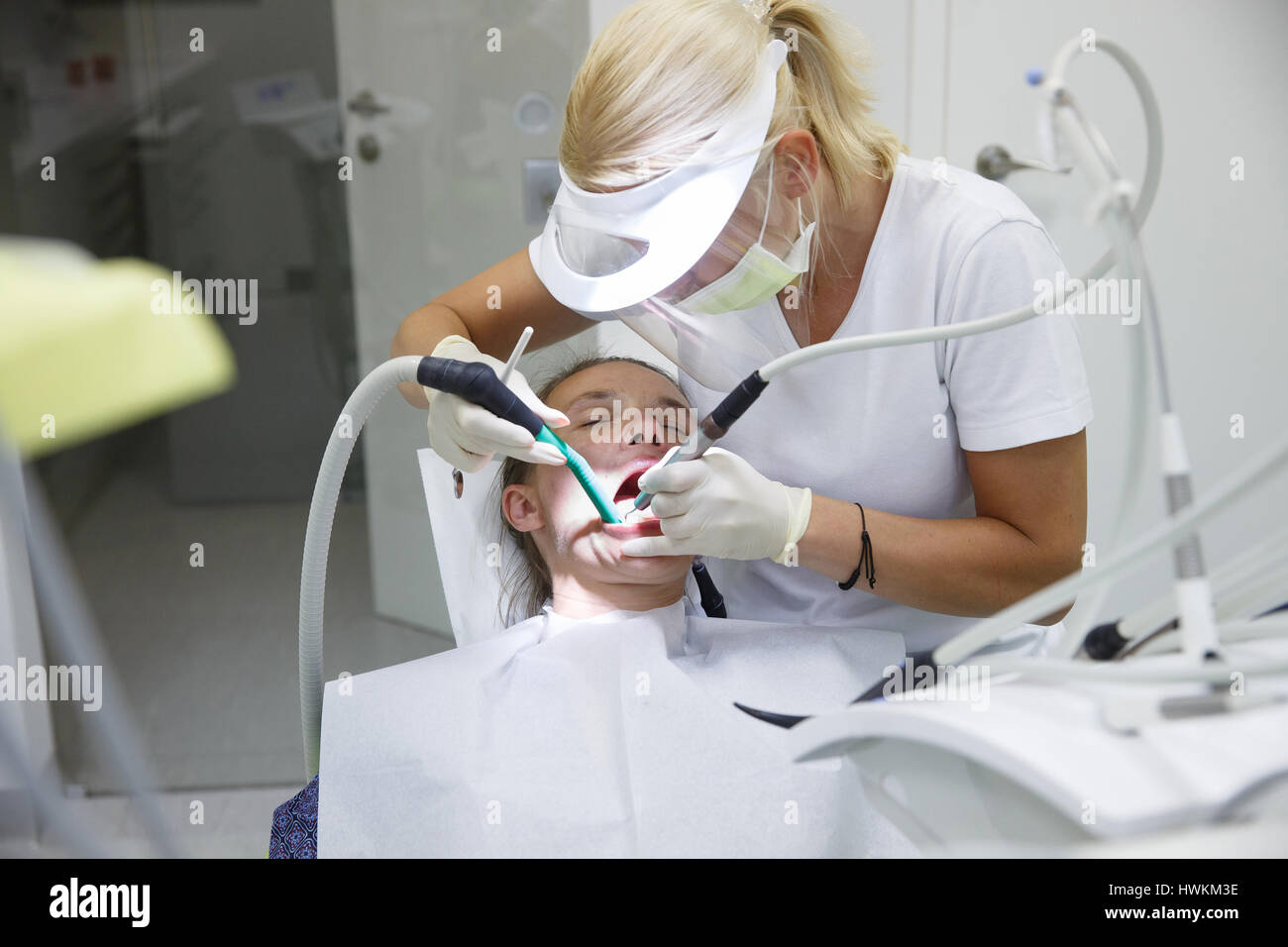 Donna in studio dentistico, dentista esaminando e pulizia i suoi denti del tartaro e della placca, prevenire la malattia periodontale. Igiene dentale, dolorose procedu Foto Stock