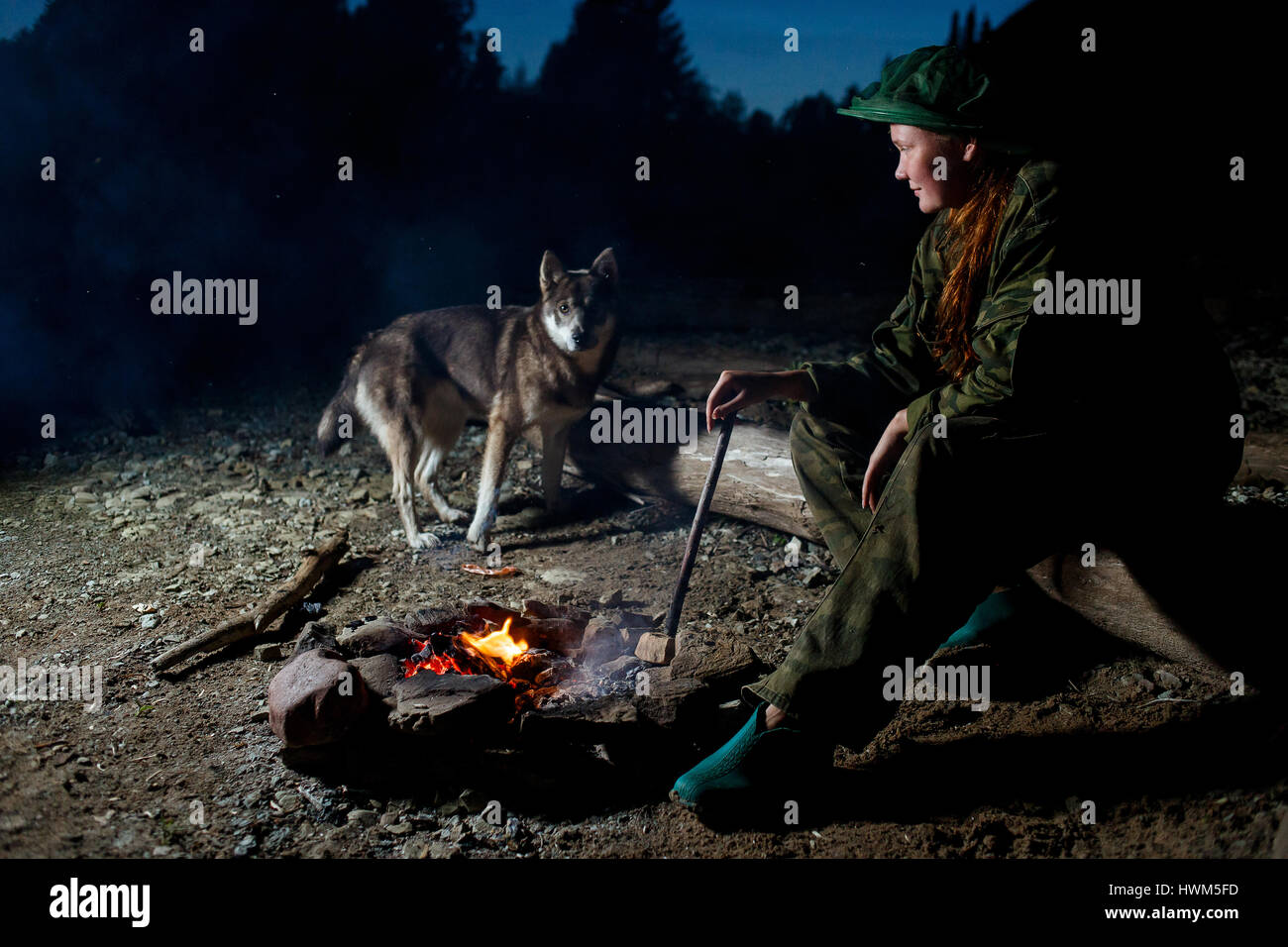 Donna con il suo cane intorno al falò di notte forest Foto Stock