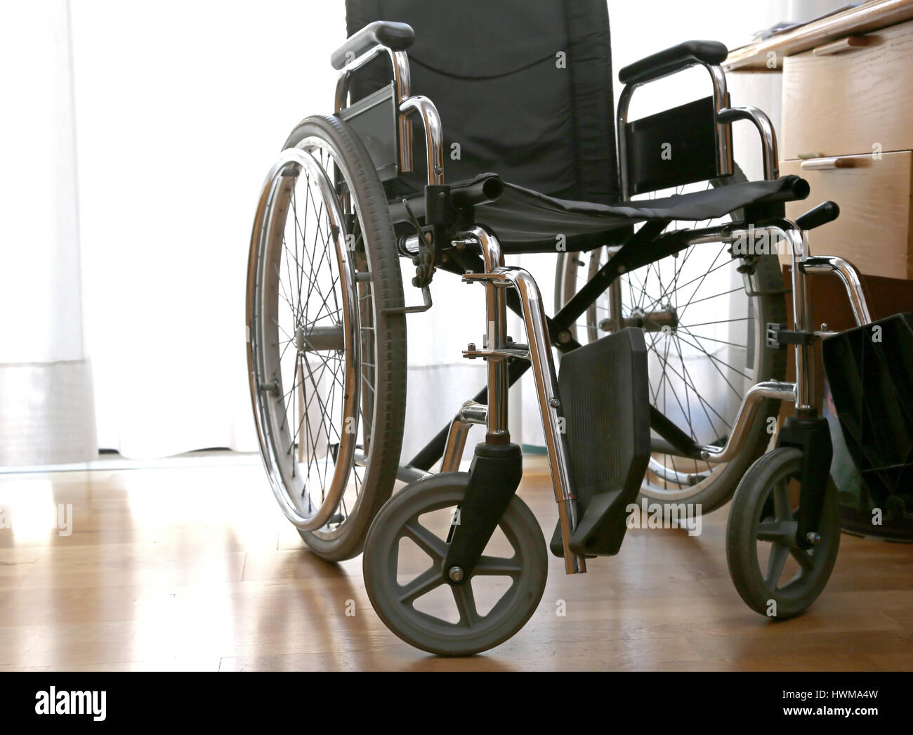 Carrozzina per disabili in una stanza con pavimento in parquet Foto Stock
