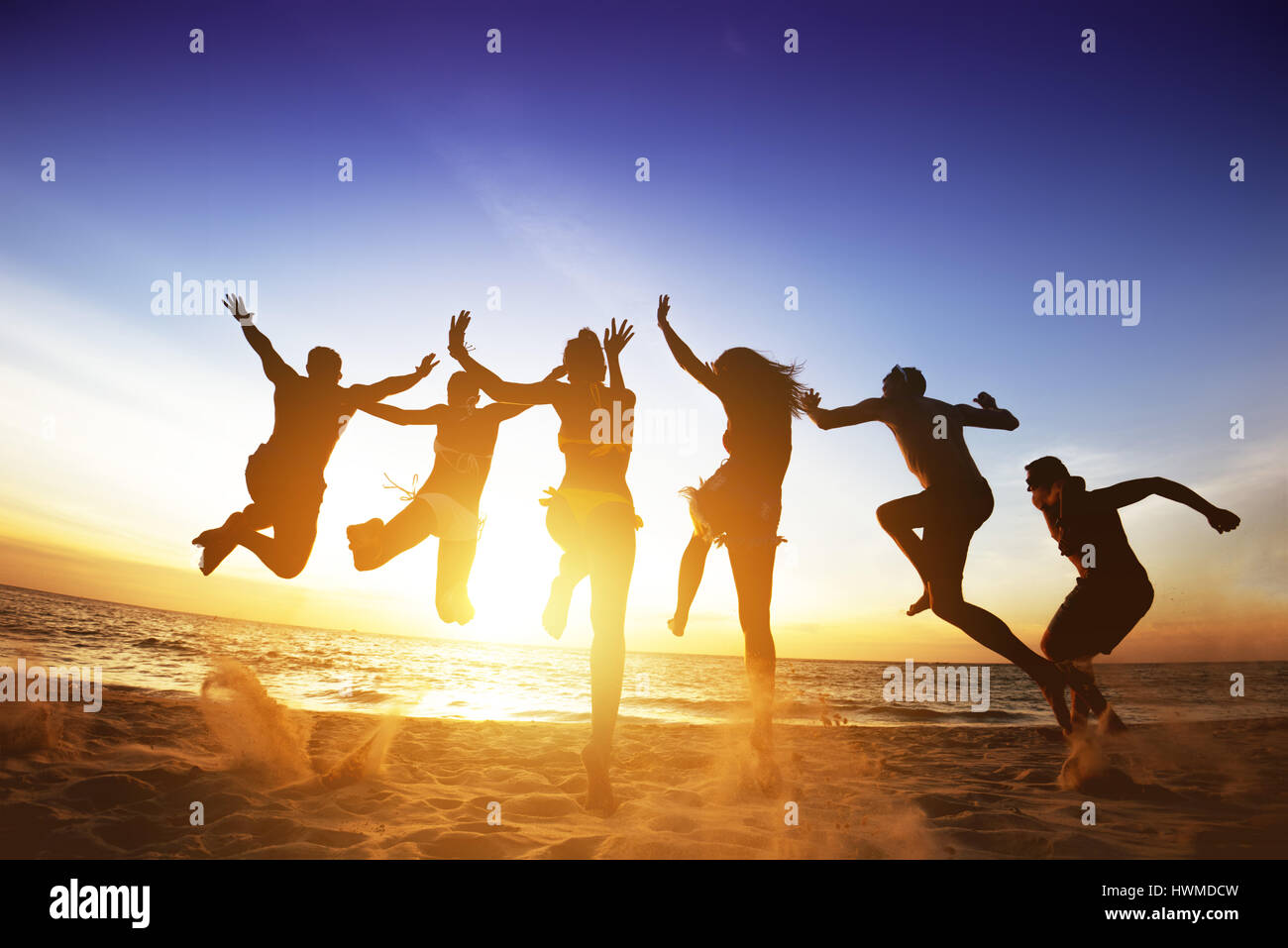 Happy amici salta al tramonto sulla spiaggia. Amicizia o concetto del team Foto Stock