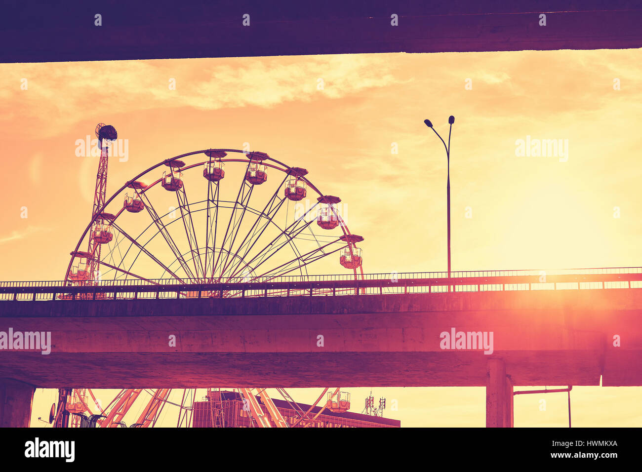 Nei toni del colore dell'immagine di una ruota panoramica Ferris contro il tramonto con lente effetto flare. Foto Stock