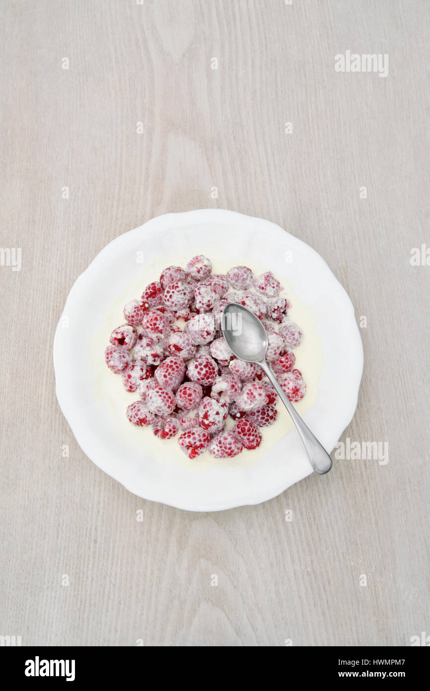 Porcellana Bianca piatto di lamponi freschi e crema con cucchiaino Foto Stock