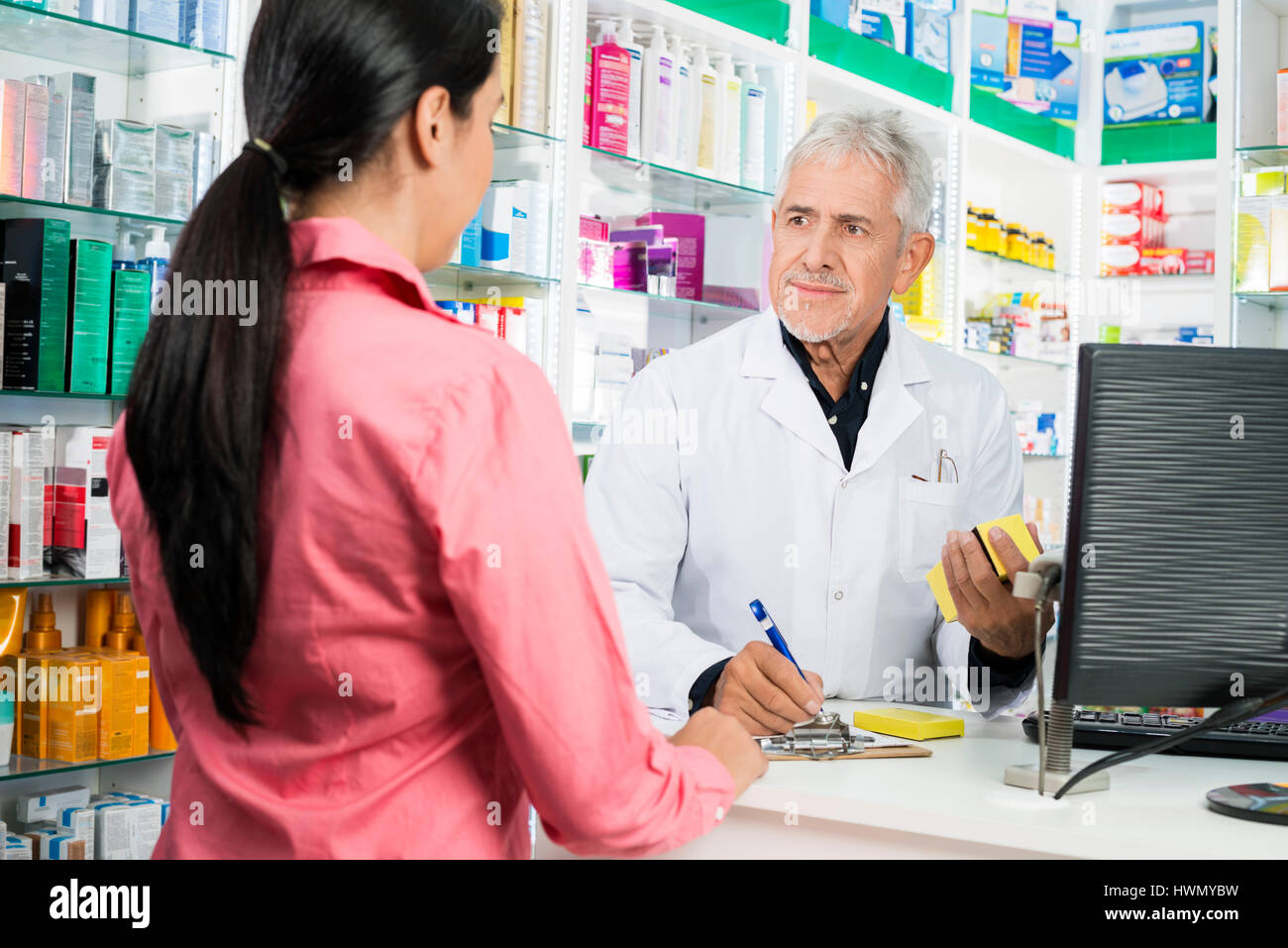 Il farmacista iscritto sulla Clipboard mentre guardando donna Foto Stock