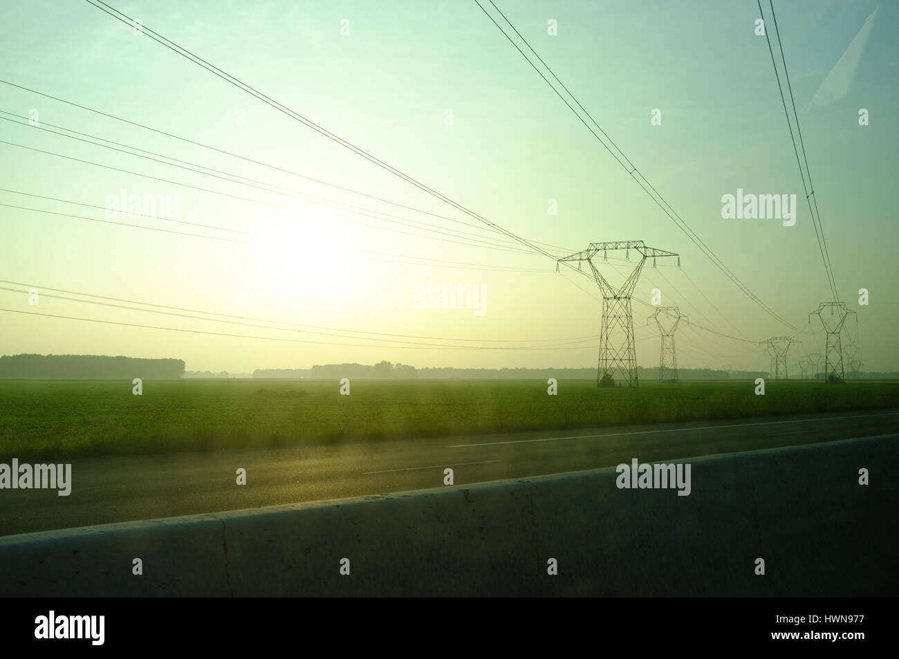 Vista di linee elettriche ad alta tensione durante il tramonto sull'autostrada, Center-Val de Loire, Francia Foto Stock