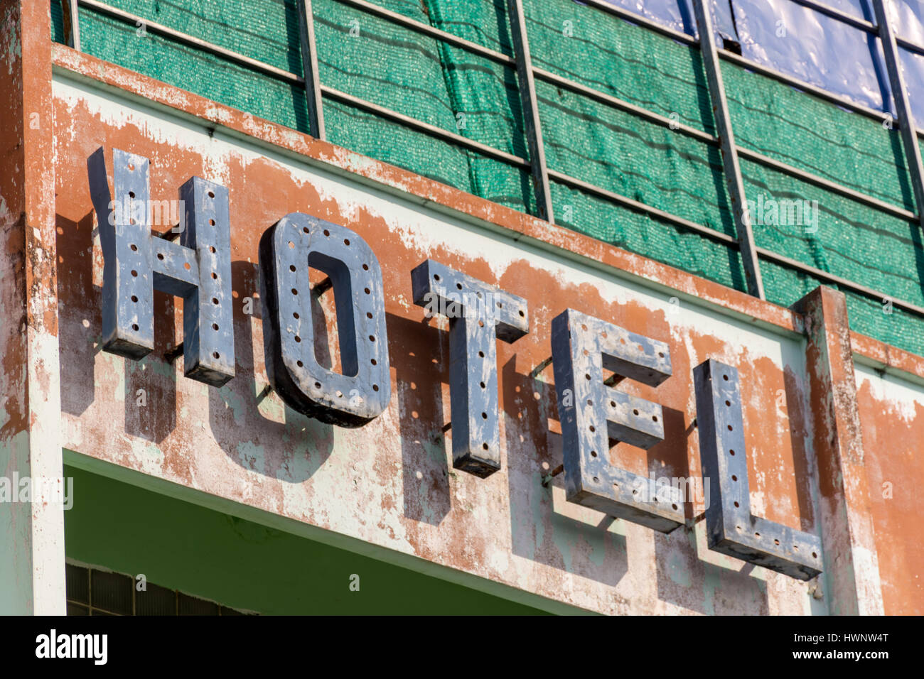 Il vecchio hotel in metallo sign in necessità di riparazione attaccato ad una parete in necessità di riverniciatura. Foto Stock
