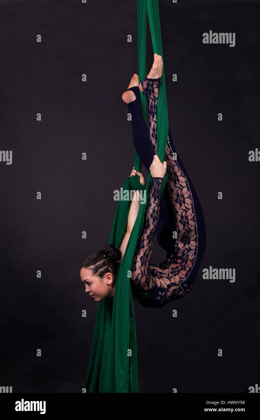 acrobazie aeree della donna nei dipinti - sfondo scuro. Studio fotografico di artisti circensi Foto Stock