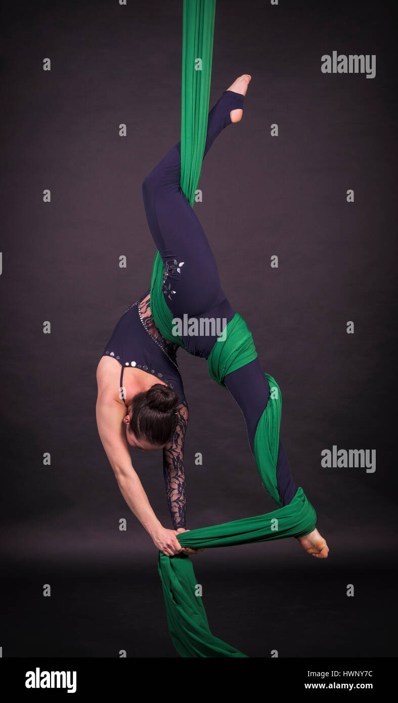 acrobazie aeree della donna nei dipinti - sfondo scuro. Studio fotografico di artisti circensi Foto Stock
