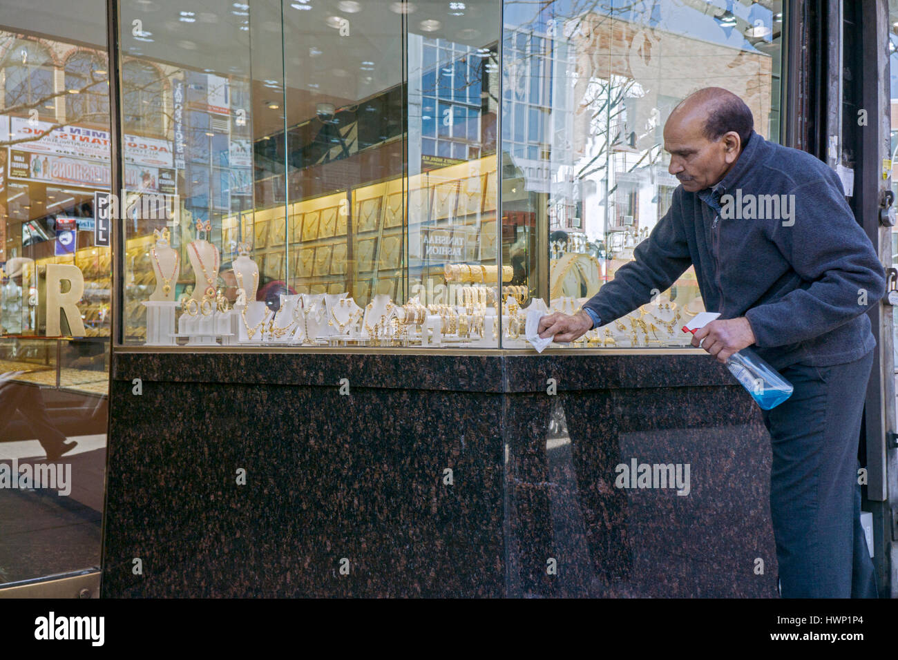 Un commerciante, probabilmente indiana, pulisce il al di fuori del suo negozio Gioielli sulla 74a Strada di Jackson Heights, Queens, a New York City Foto Stock