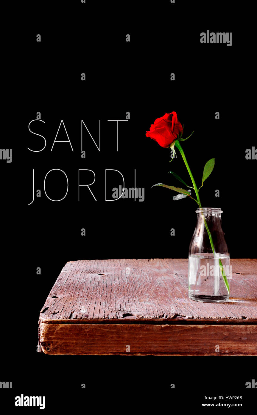 Una rosa rossa in un vaso collocato su un tavolo di legno, su uno sfondo nero e il testo Sant Jordi, catalano di nome per il Saint Georges giorno, quando è Foto Stock