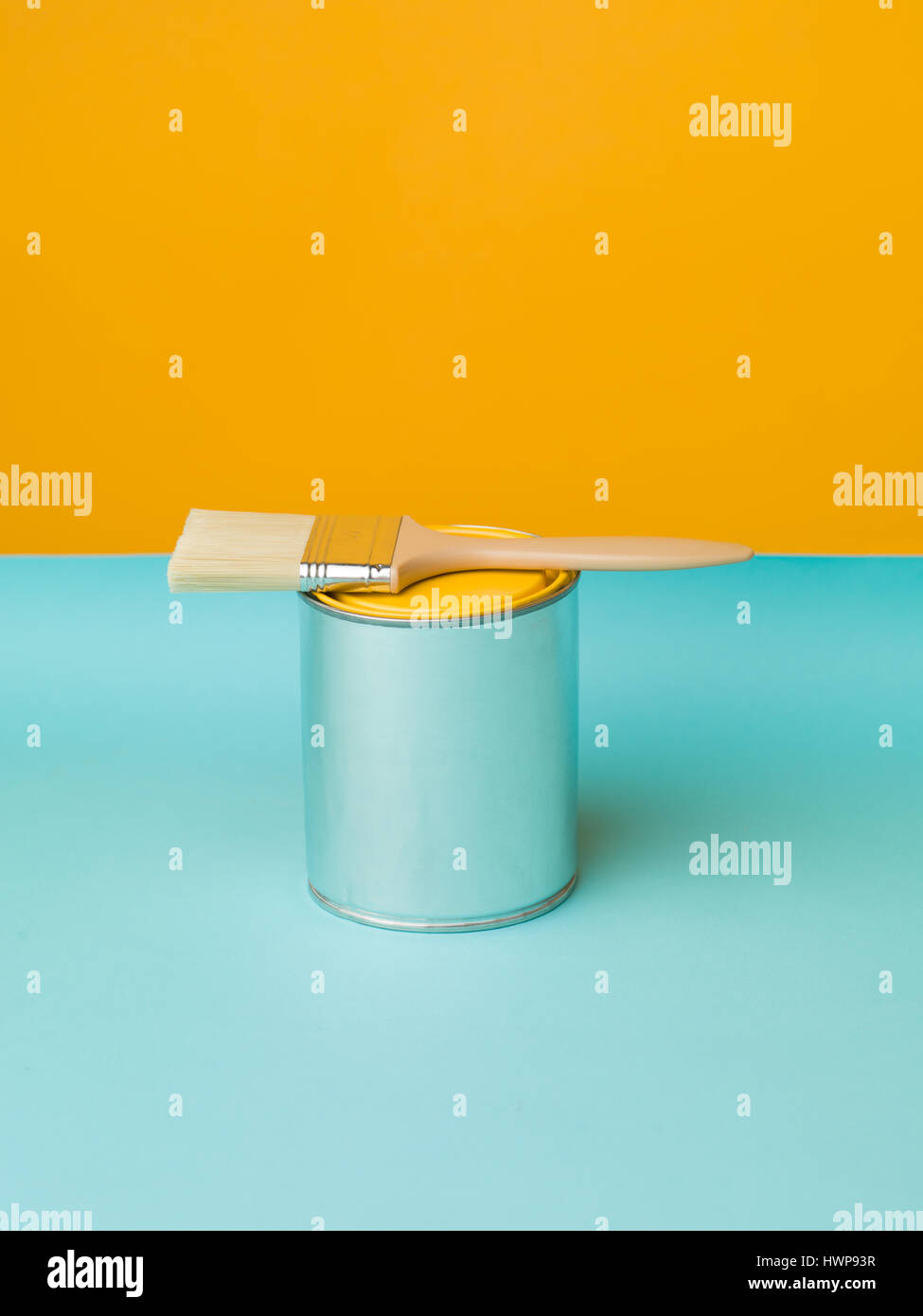 Immagine minima dipinta di fresco sfondo giallo e può con spazzola sul tavolo blu. Tema di rinnovamento con spazio di copia Foto Stock