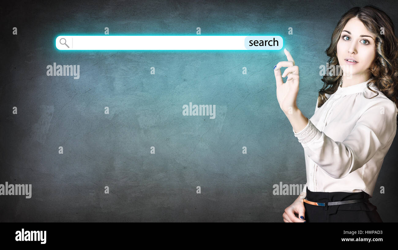 Giovane imprenditrice spingendo la ricerca digitale pulsante sopra la parete scuro dello sfondo. Foto Stock