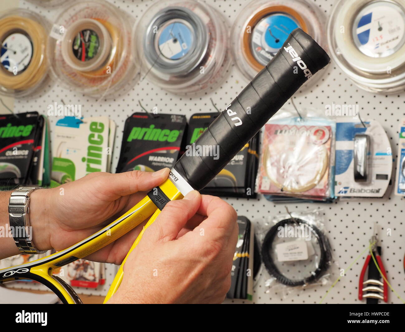 Melbourne, Australia, 2015 10 Maggio: Avvolgimento del nastro di rifinitura su una fresca avvolto racchetta da tennis grip di base in un pro shop con l'ingombro di materiali di consumo Foto Stock