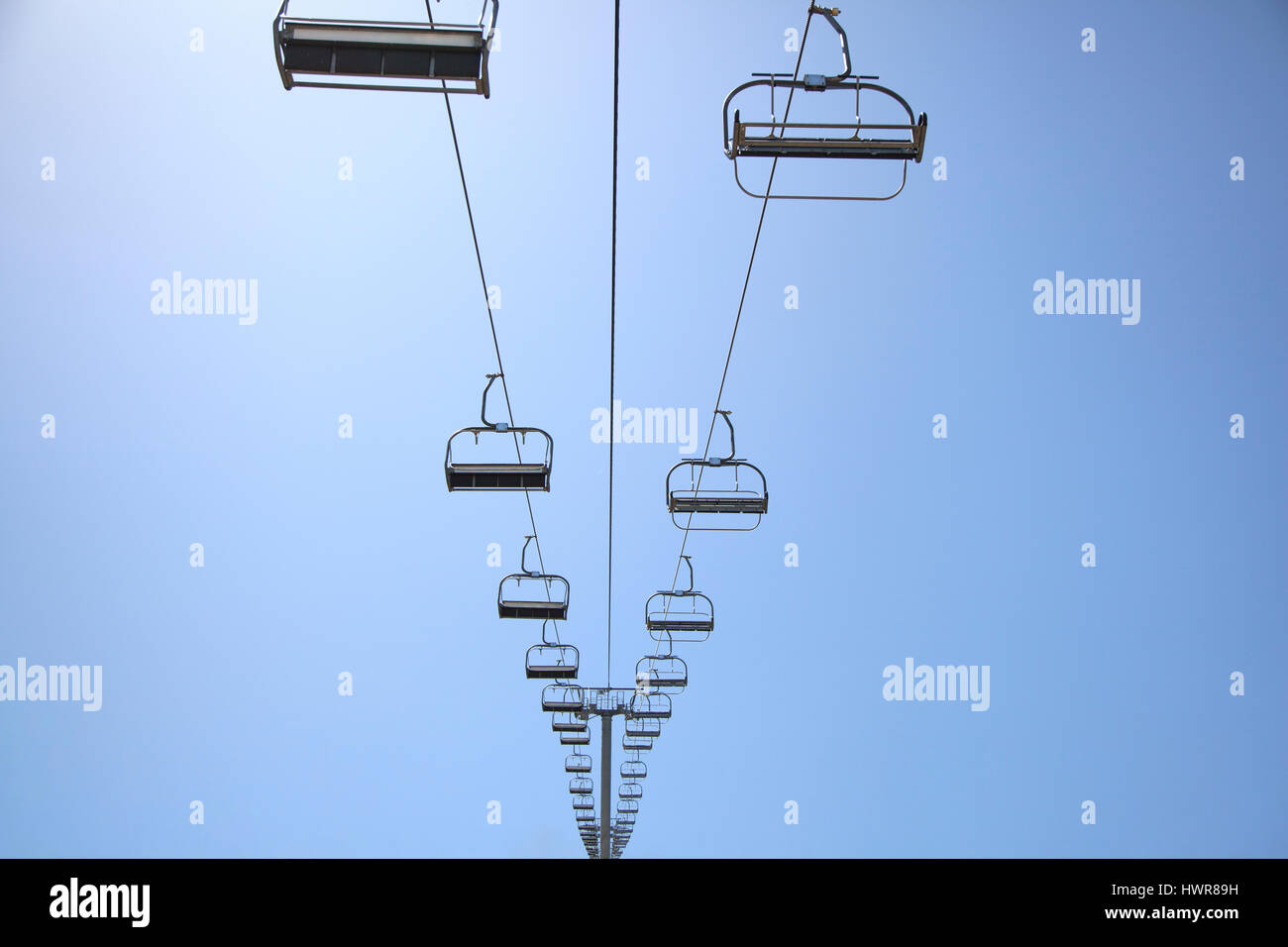 Sedia vuota ski lift in montagna su un cielo blu sullo sfondo. Foto Stock