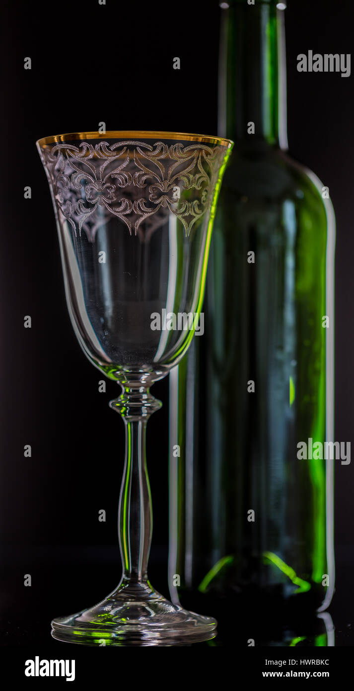Il vino rosso di vetro e una bottiglia di vino su sfondo nero Foto Stock