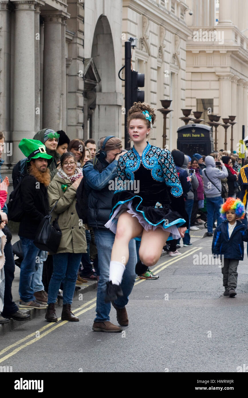 Ballerino di danza irlandese nel tradizionale costume irlandese che saltava e danzava sulle strade di Londra per il giorno di San Patrizio parade Foto Stock