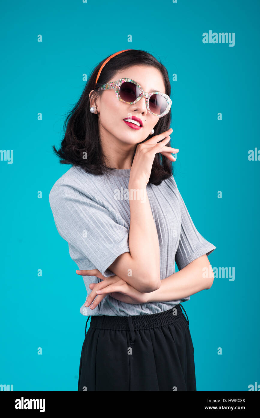 Corpo pieno di sorridere donna asiatica vestita di pin-up stile di vestiti che indossa occhiali su blu. Foto Stock