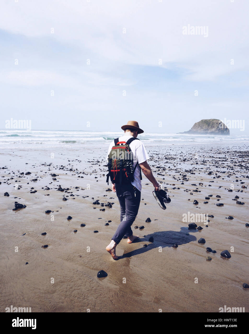 Vista posteriore di un escursionista a piedi su bagnato spiaggia sabbiosa contro sky durante la giornata di sole Foto Stock