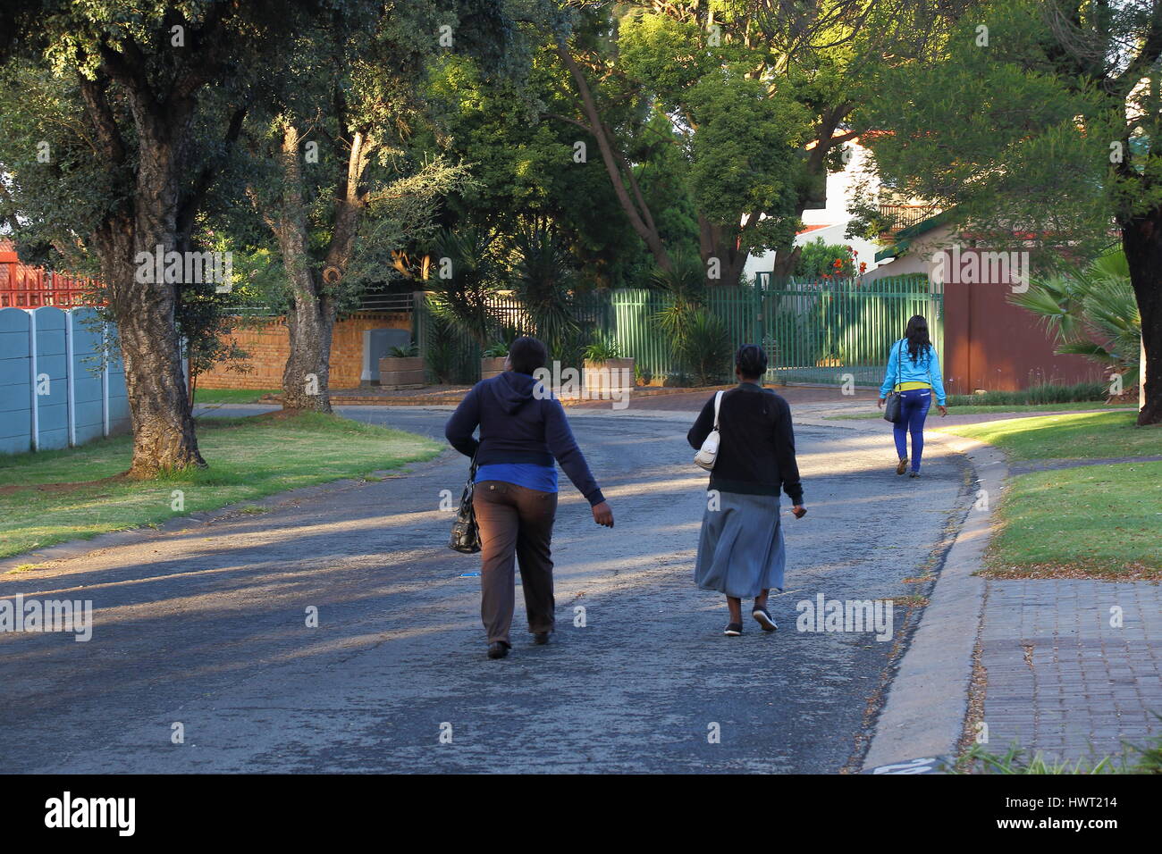 I lavoratori neri a piedi a lavorare attraverso un sobborgo residenziale in post-apartheid in Sud Africa a causa della mancanza di infrastrutture di trasporto pubblico Foto Stock