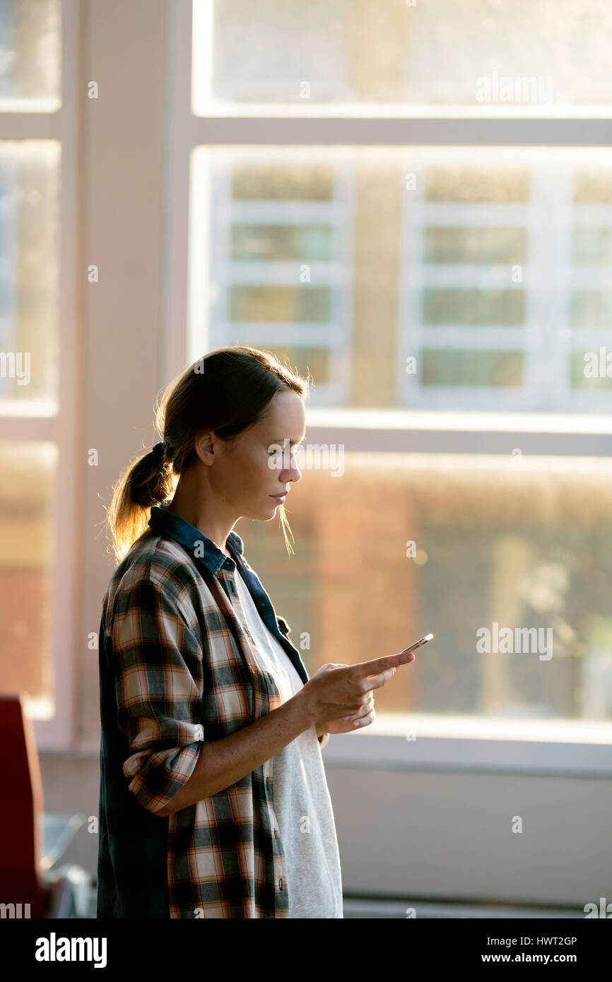 Donna che utilizza un cellulare in aeroporto area di partenza Foto Stock