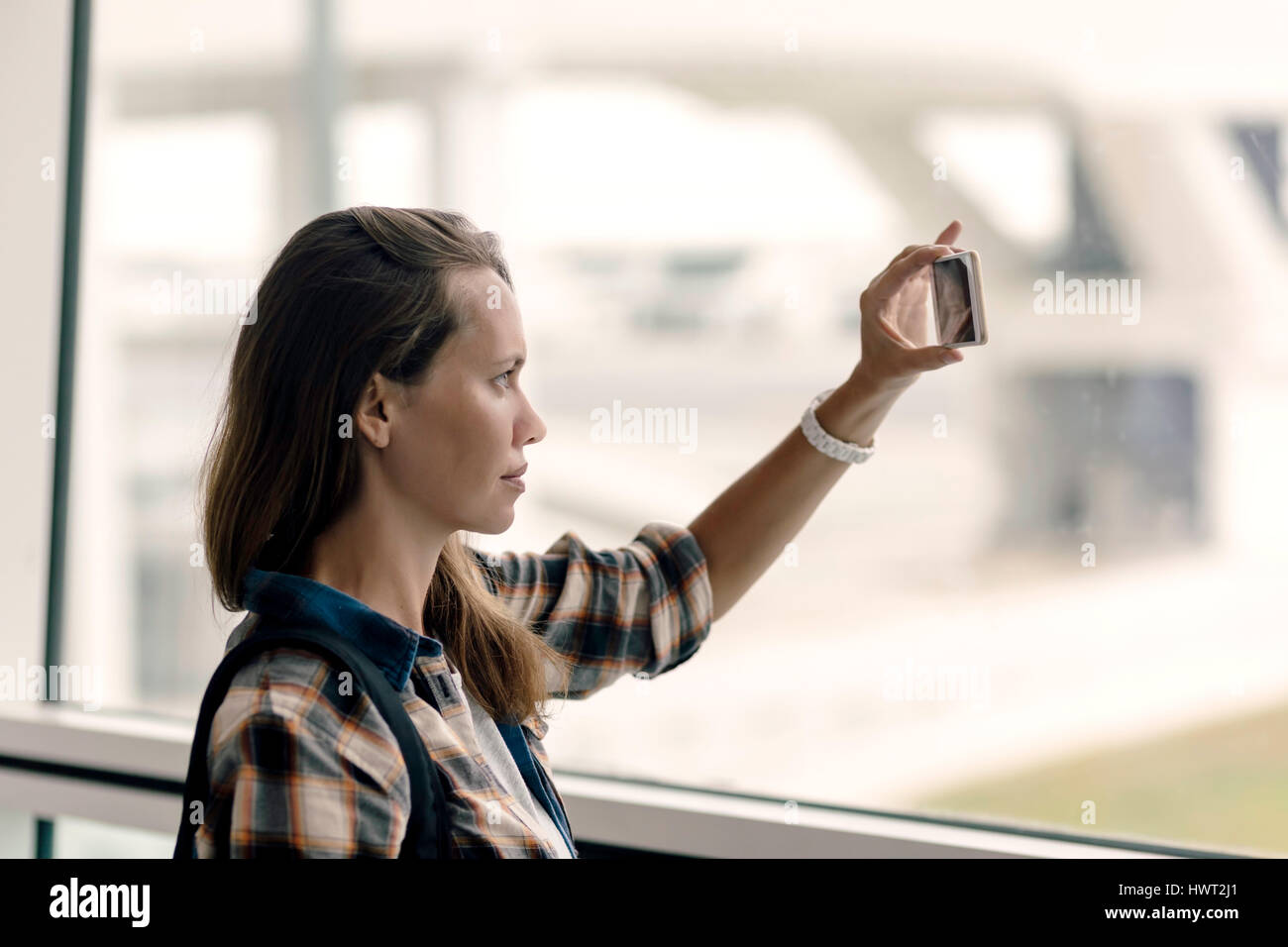 Donna fotografare mentre in piedi in aeroporto area di partenza Foto Stock