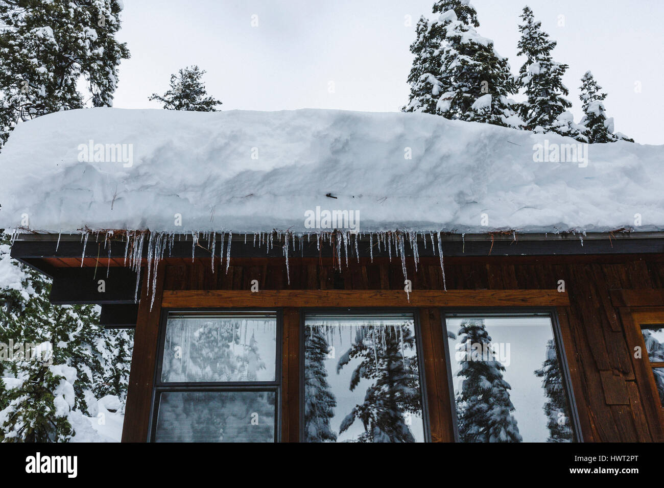 Basso angolo vista di neve sul tetto della casa con ghiaccioli Foto Stock