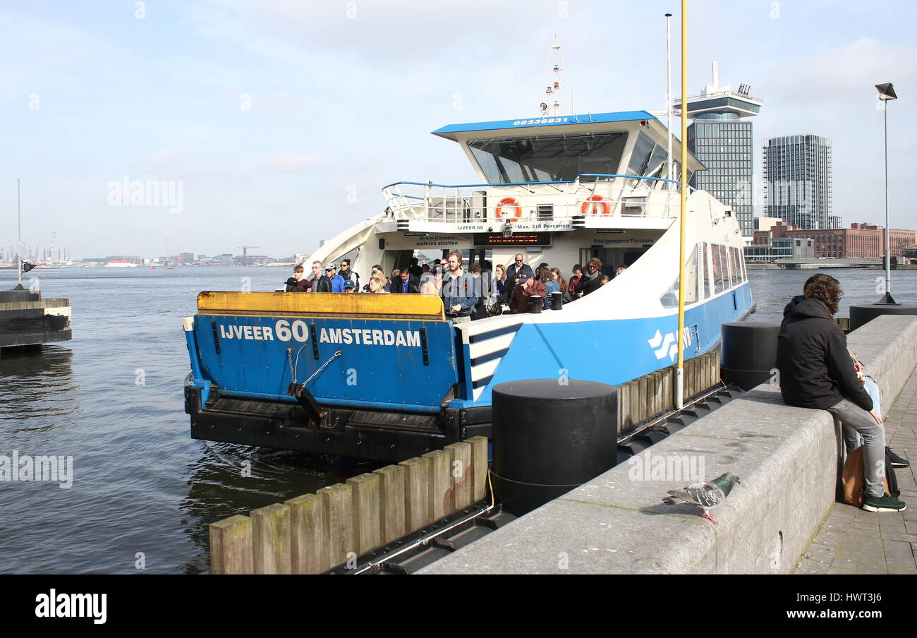 Pedone e bicicletta Ferry Crossing presso il fiume IJ dietro la stazione centrale di Amsterdam, Paesi Bassi. Occhio film museum e un'DAM torre in background Foto Stock