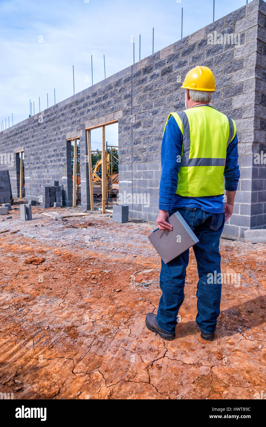 Un grey-haired supervisore di costruzione ispeziona un nuovo edificio retail job. Foto Stock